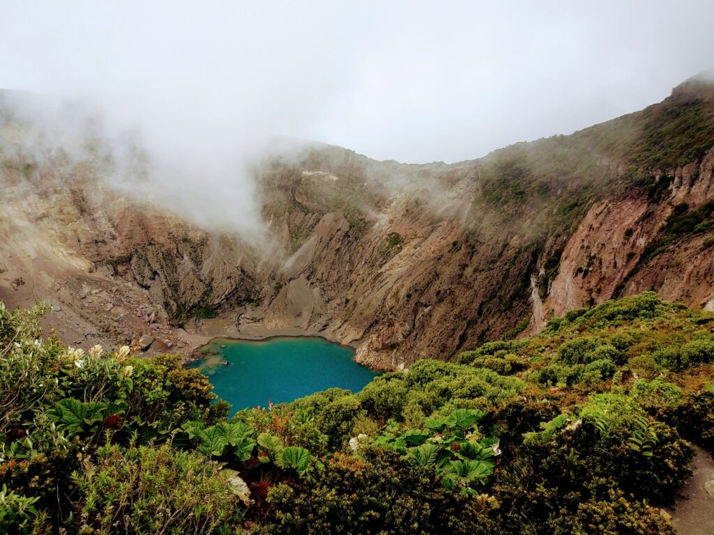 Um pequeno lago numa região vulcânica com vegetação e rochas ao redor. Vulcão Irazú na Costa Rica para representar seguro viagem para Costa Rica