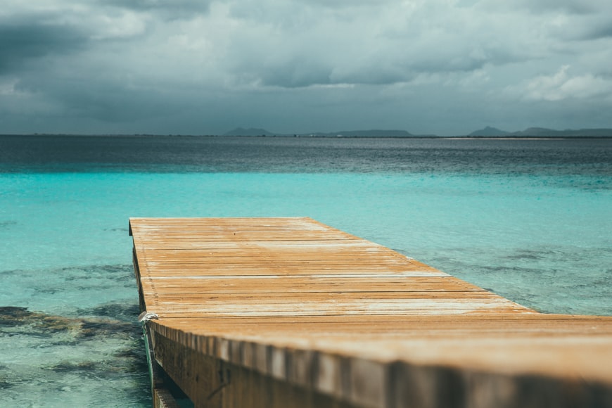 Mar azul de frente com doca de madeira. Klein Bonaire, Países Baixos Caribenhos representa o seguro viagem para Bonaire