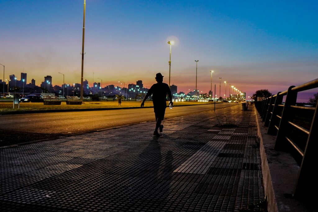Uma pessoa de costas andando numa avenida iluminada de noite. Seguro viagem para o Paraguai.