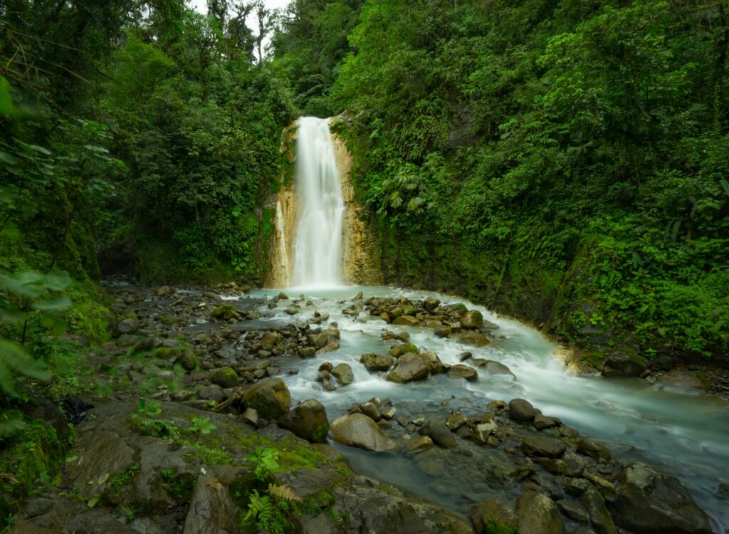 Queda de uma catarata por entre montanhas, vegetação e pedras, conhecida como Cataratas Las Gemelas