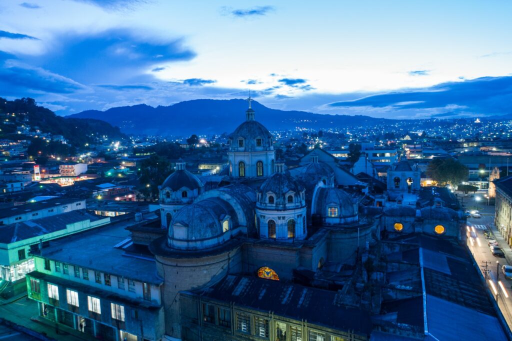 Prédios históricos junto com casas, montanhas ao fundo, na Cidade de Guatemala para representar seguro viagem América Central