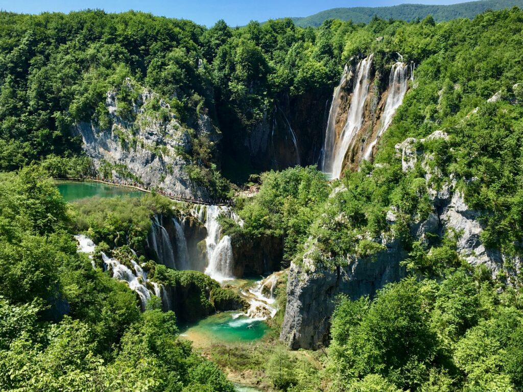 Parque Nacional dos Lagos de Plitvice na Croácia, diversas cascatas que formam um lago de águas esverdeadas por entre rochas, montanhas e muita vegetação, para representar o seguro viagem para Croácia