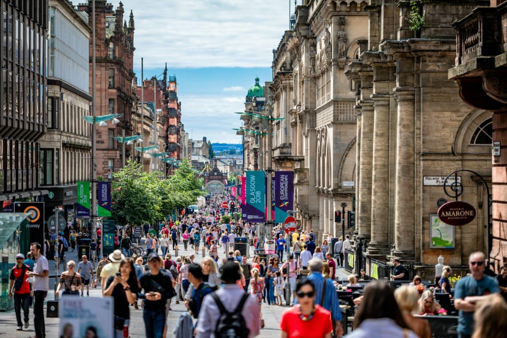 Ruas centrais de Glasgow com muitas pessoas caminhando, um enorme calçadão com lojas, restaurantes e bares, os prédios são antigos e com arquitetura em estilo vitoriano, para representar o seguro viagem para Escócia