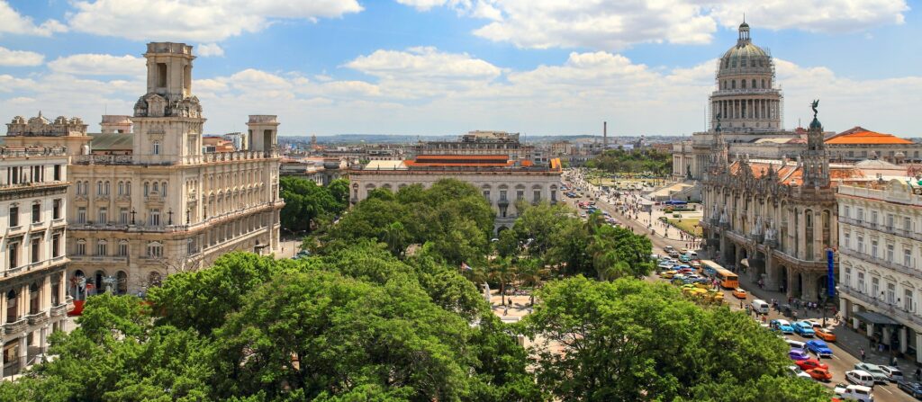 Capital de Cuba, Havana com prédios históricos e antigos com uma praça cheia de árvores no centro da foto para representar seguro viagem América Central