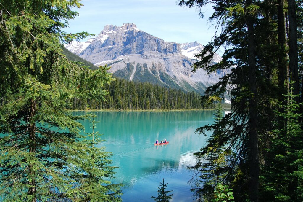 Lago com águas límpidas cercado por vegetação e, ao fundo, montanhas no Lago Moraine no Canadá para representar seguro viagem para América do Norte