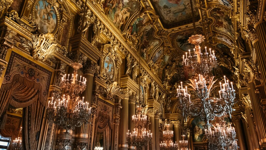 Parte interna do Palácio Garnier com uma decoração renascentista, pinturas, lustres, tudo em tom de ouro 