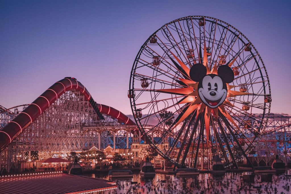 Montanha-russa e uma roda gigante com o rosto do Mickey estampado no parque de diversão da Disney em Orladno
