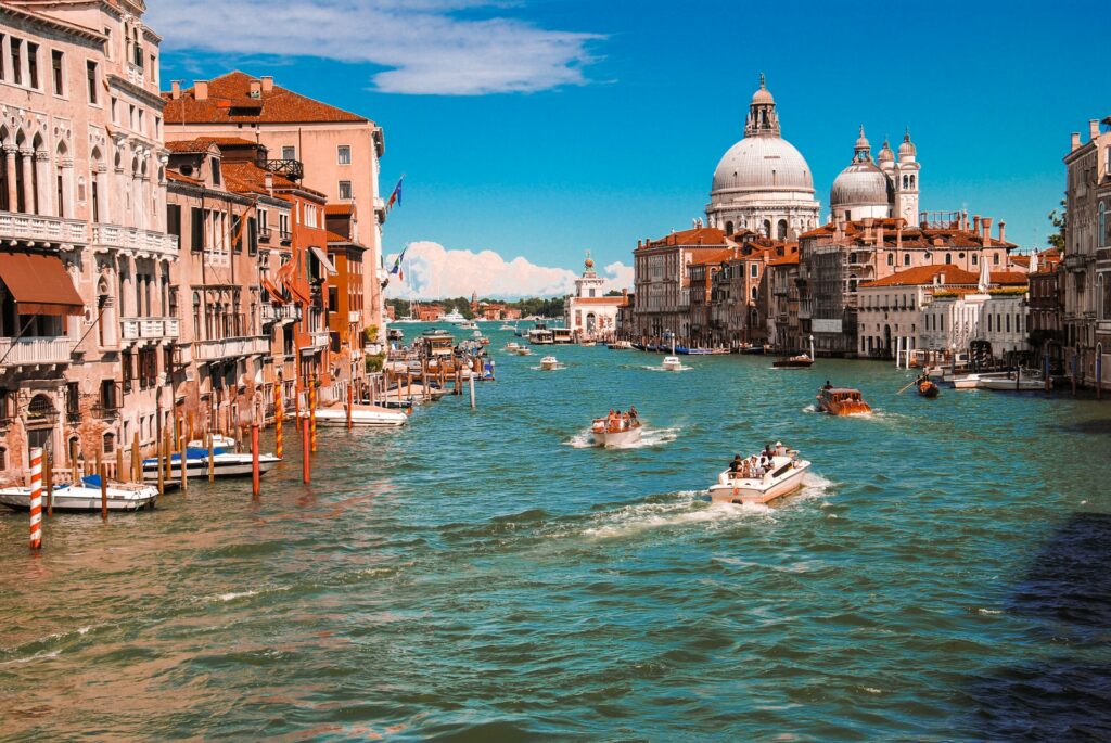 Pequenos barcas andando por um rio que cortas a cidade em Veneza na Itália