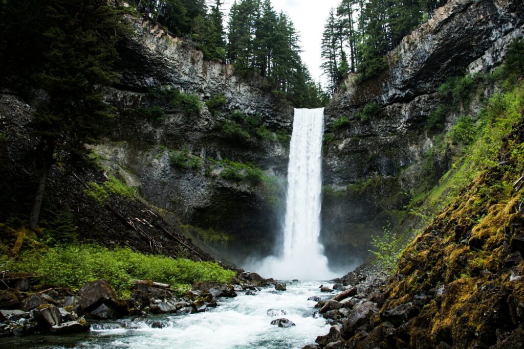 Cascata d'água por entre uma montanha com rochas e vegetação em Brandywine Falls Provincial Park em Whistler no Canadá para representar o seguro viagem para Whistler