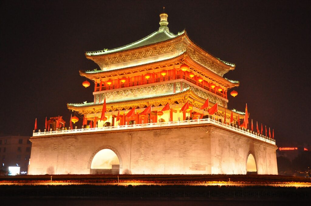 A torre de um templo iluminada de noite em Xian na província de Shaanxi, a construção segue a arquitetura chinesa com telhados pontudos, muitos desenhos e a cor vermelha predominante, para representar o seguro viagem para China