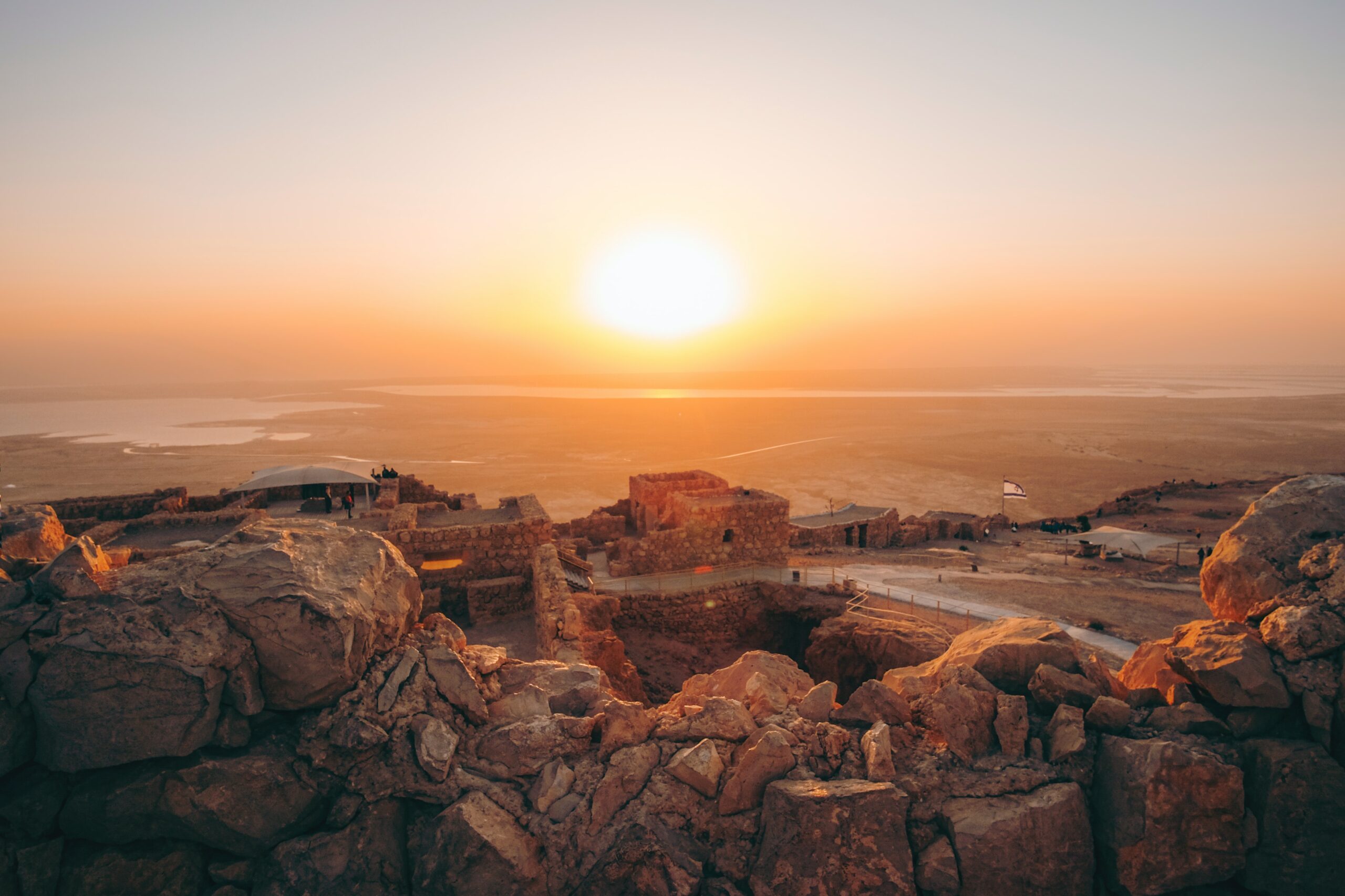 Vista do pôr do sol no parque Masada, Israel, com muros e monumentos feitos de pedras. Representa seguro viagem Israel.