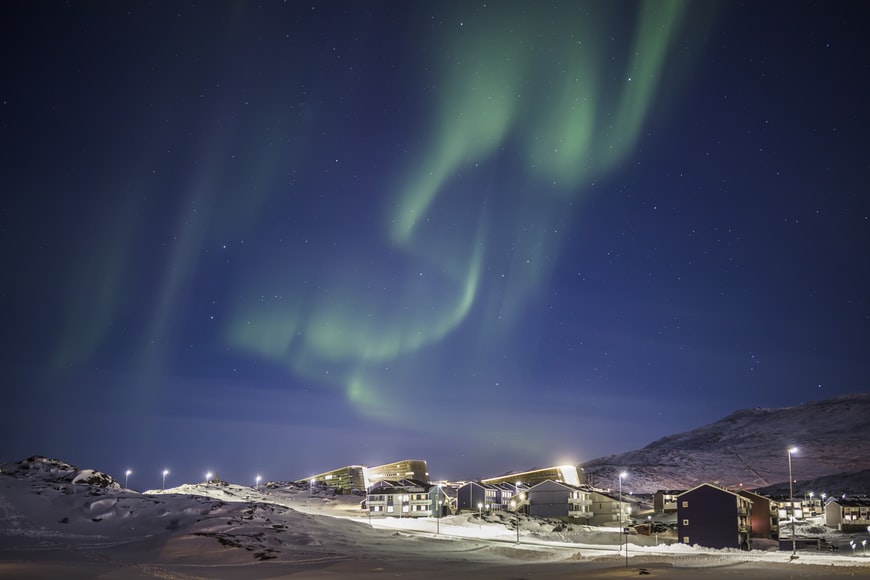 Aurora boreal a noite na cidade de Nuuk, Groenlândia. Representa o seguro viagem para Groenlândia.