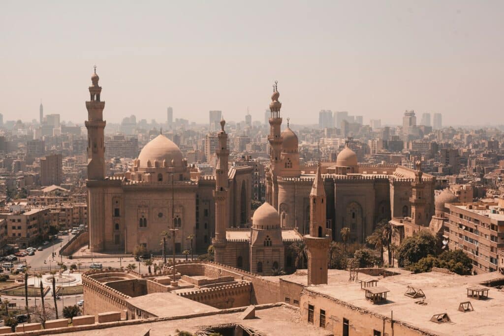 Construção histórica de Mesquita de Rifai e Sultan Hassan no Cairo  com torres em diversos tamanhos e formatos arredondados em tons de bege e marrom, para representar o seguro viagem para o Egito