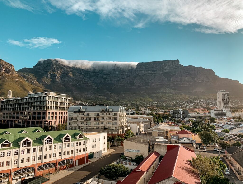 Uma cidade com prédios de arquitetura antiga e um enorme paredão de rochas ao fundo na Cidade do Cabo a capital da África do Sul para representar o seguro viagem para África do Sul