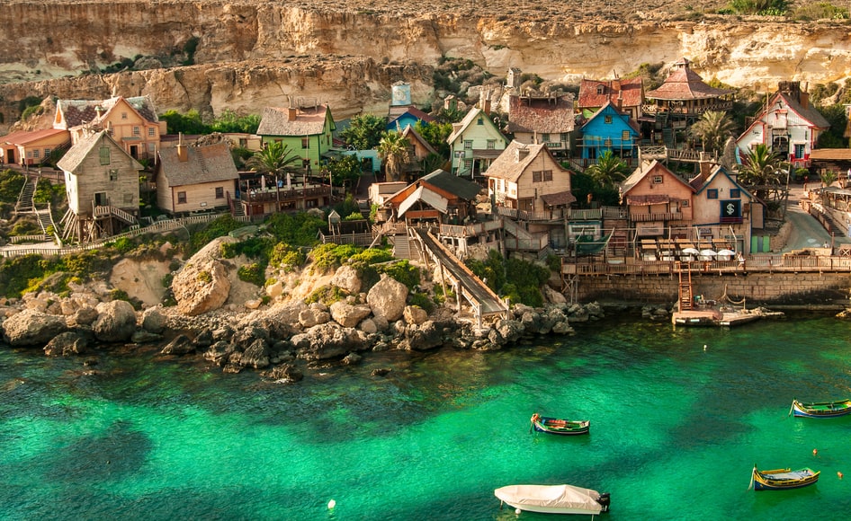 Mar verde esmeralda com casa de madeiras em volta Popeye Village,Mellieha ,Malta- Representa seguro Viagem Malta

