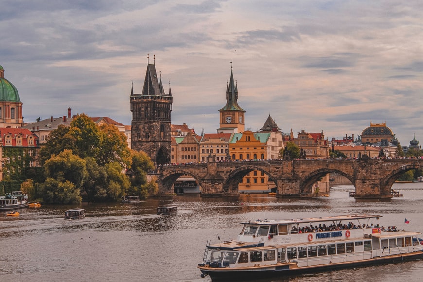 Prédios e ponte com um rio e um barco em Praga, República Tcheca -Representa seguro viagem República Tcheca