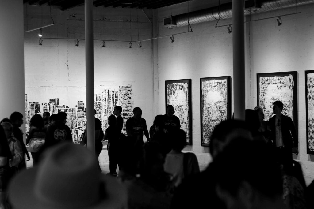 Galeria de arte Wynwood Walls com pessoas observando quadros que estampam rostos 
