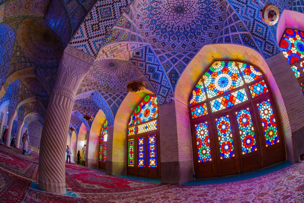 Nasir al-Mulk Mosque na Província de Fars no Irã, um local muito colorido, com vitrais em azul, verde, vermelho, formando desenhos circulares que lembram flores, tapetes persas pelo chão, teto inteiro desenhado com mosaicos, para representar o seguro viagem para o Oriente Médio
