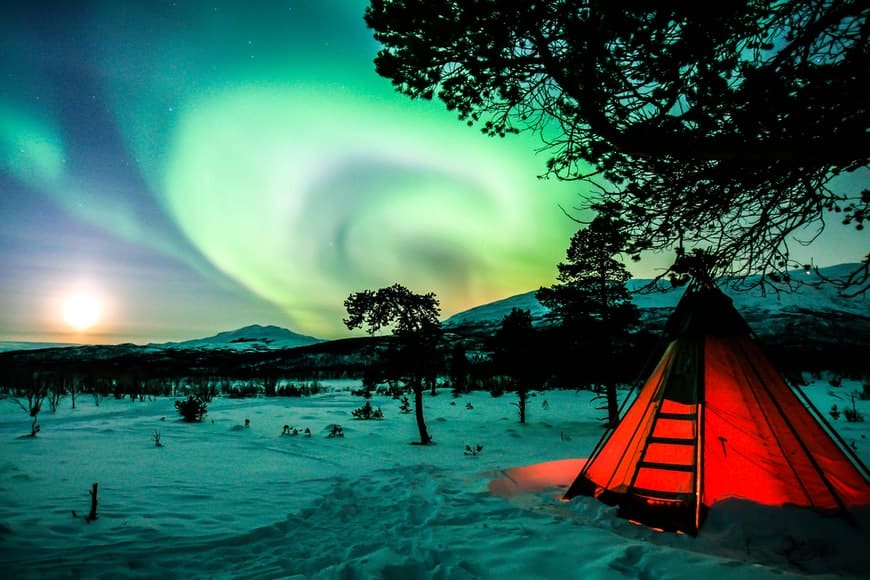 Aurora boreal em meio a neve em Abisko, Suécia.