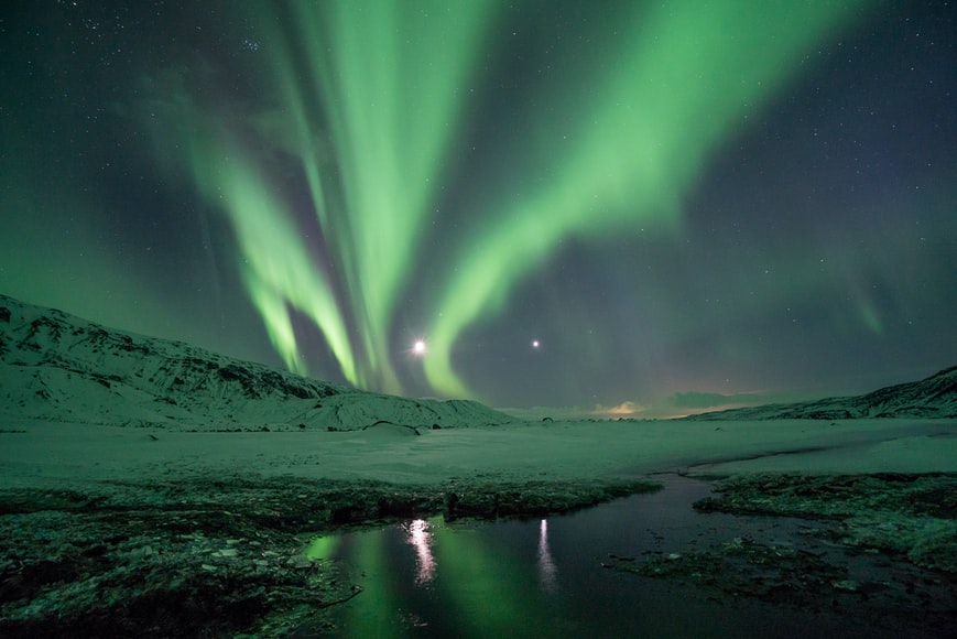 Aurora boreal em meio as montanhas cobertas de neve em Thórsmörk, Islândia.