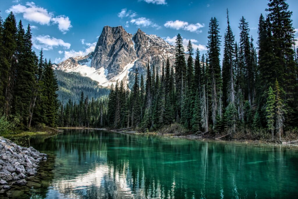 Lago límpido cercado por vegetação e montanhas nevadas ao fundo em Colúmbia Britânica no Canadá para representar o seguro viagem para Colúmbia Britânica