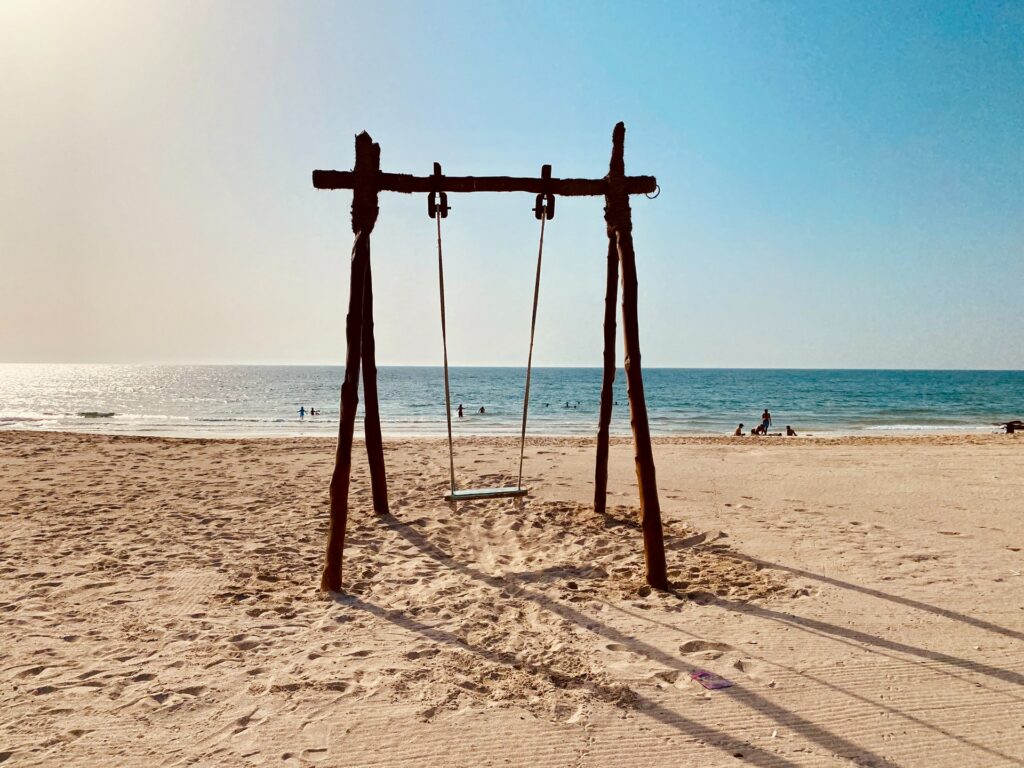 Um balanço de madeira preso na areia de uma praia chamada Khor Fakkan Beach em Sharjah nos Emirados Árabes