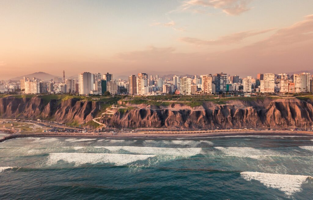 Cidade ao fundo, em seguida, uma parede de rochas, uma avenida e o início da praia em Costa Verde em Lima no Peru
