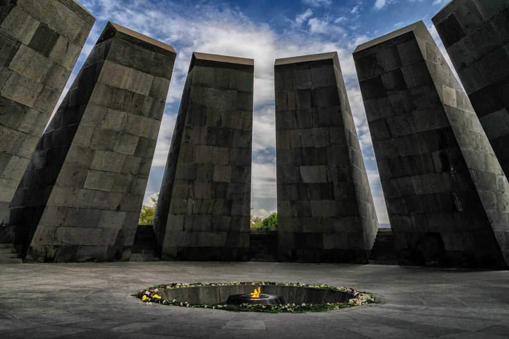 Memorial do Genocídio Armênico em Erevan, capital da Armênia, uma construção com torres quadradas feitas de tijolo e extremamente altas formam uma espécie de círculo, e no centro, é possível ver uma fagulha de fogo que fica acessa com flores ao redor, para representar o seguro viagem para Armênia
