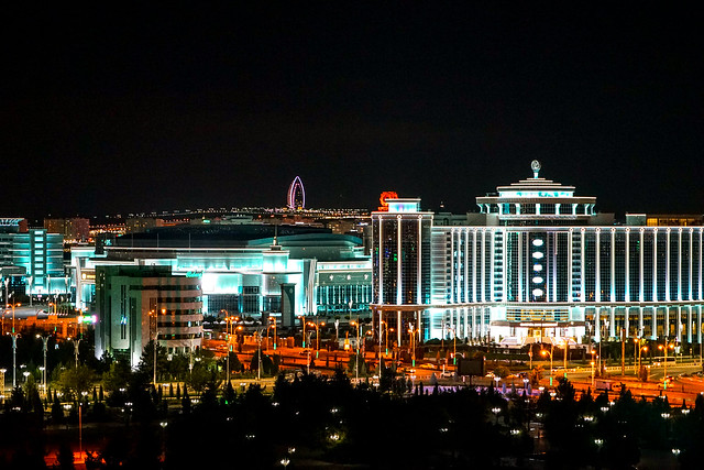 Ashgabat, capital do Turcomenistão, uma cidade iluminada de noite com prédios luxuosos e muitas árvores pelas ruas, para representar o seguro viagem para Turcomenistão