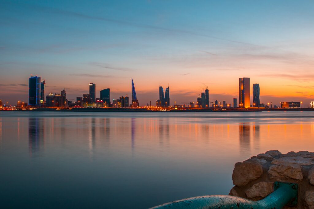 Al Muharraq, cidade no Barein, uma cidade com prédios luxuosos virados para o mar, com montanhas e nuvens ao fundo, com o céu de entardecer, para representar o seguro viagem para Barein