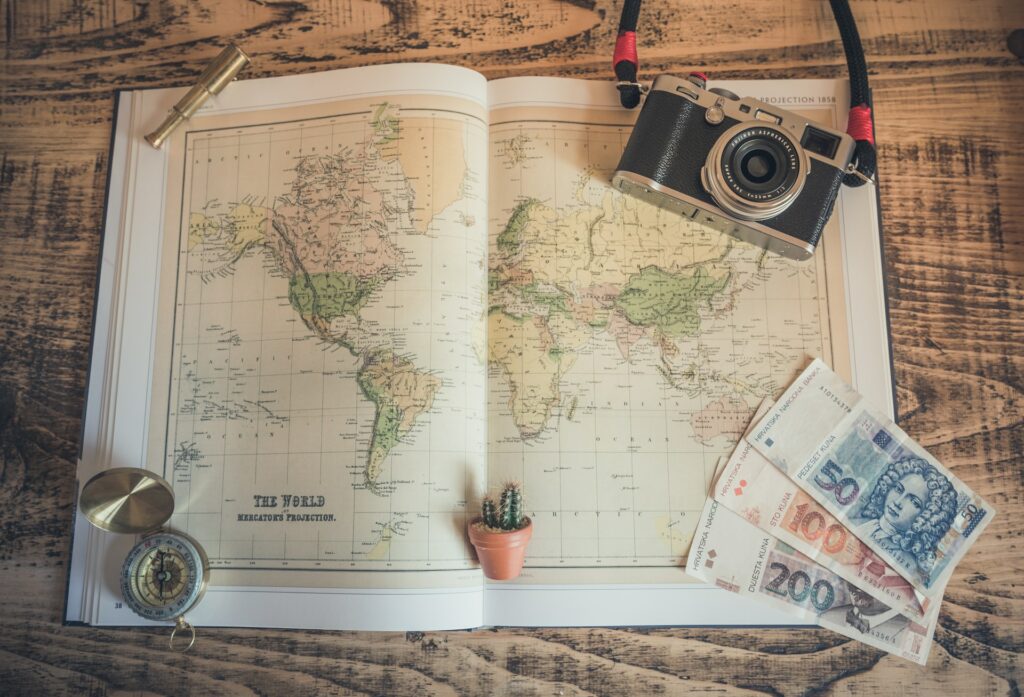 Um mapa aberto com uma câmera fotográfica em cima, uma bússola e algumas notas de dinheiro para representar o seguro viagem para Suriname