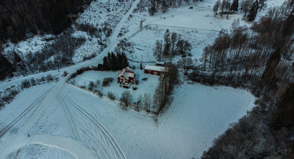 Região de Sognsvann, com uma casa no meio da neve, cercada por montanhas nevadas, algumas árvores, para representar o seguro viagem para Oslo