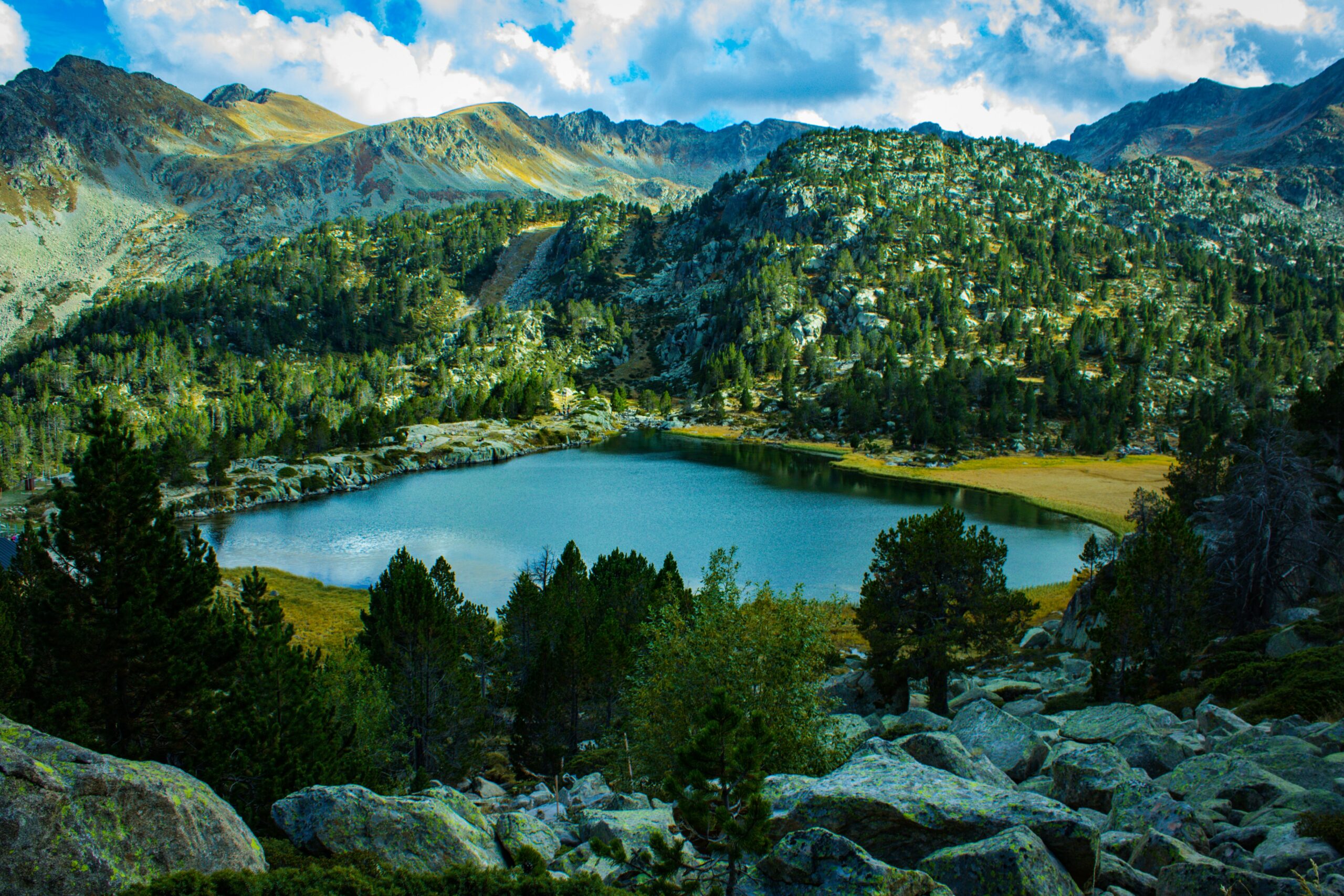 Vista do lago Estanys de Tristaina, Andorra com aguas claras envolta de floresta. Representa o seguro viagem para Andorra.