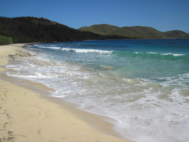 Praia Tamarindo, uma praia de areia bem clara, mar em tons de azul e verde, ao fundo, muitas montanhas, para representar o seguro viagem para Ilhas Virgens Espanholas