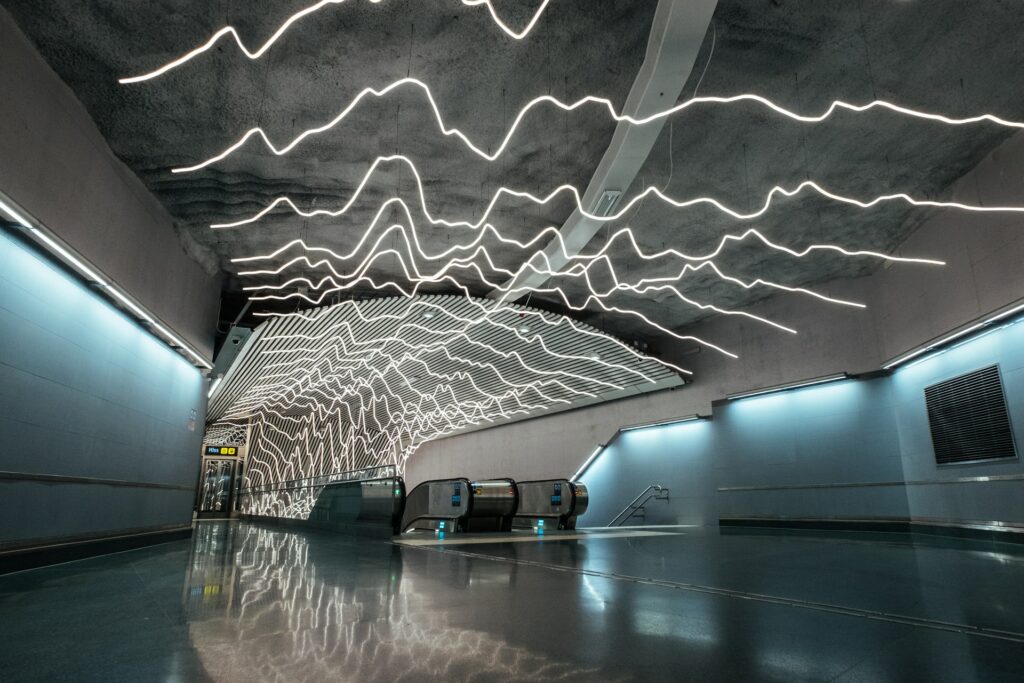 Uma estação do metrô em Odenplan na cidade de Estocolmo, o teto tem diversas linhas brancas e iluminadas que se parecem com ondas sonoras, iluminando todo o local e chamando a atenção pela intervenção artística, para representar o seguro viagem para Estocolmo