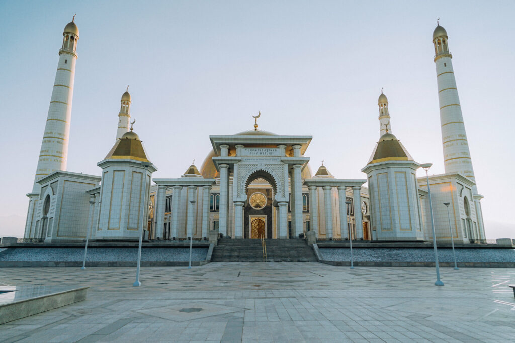 Mesquita de Kipchak em Turcomenistão, uma construção branca com detalhes em ouro com um enorme pátio na frente, para representar o seguro viagem para Turcomenistão