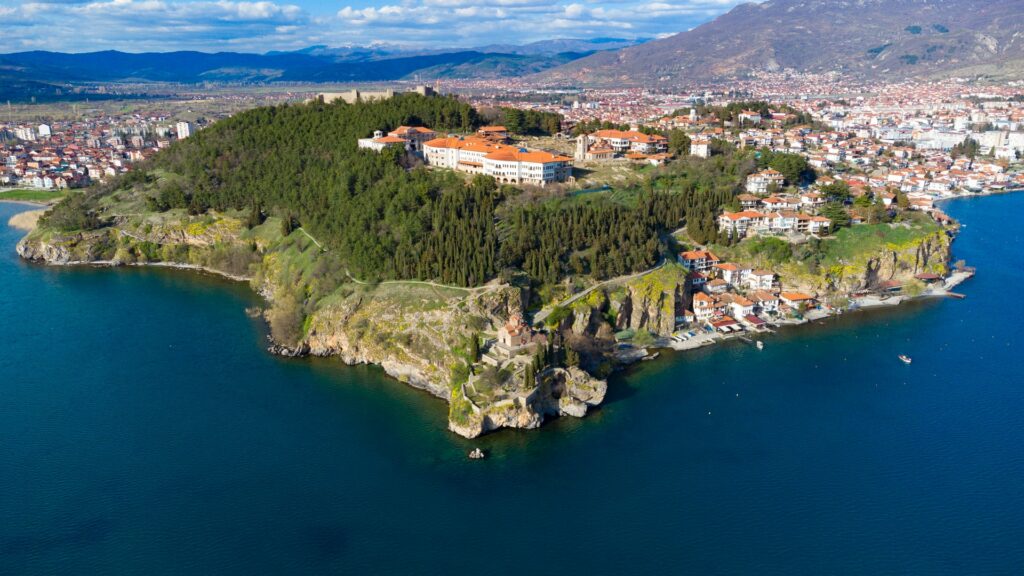 Ohrid, cidade da Macedônia, um castelo sob uma enorme rocha que se estenda para a cidade, cercada pelo mar azul escuro, muitas árvores e uma montanha surge após a cidade, para representar o seguro viagem para Macedônia
