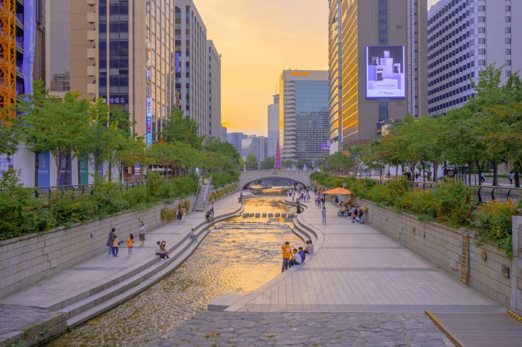 Cheonggyecheon, um riacho no centro da cidade de Seul, com locais para as pessoas sentarem, a cidade está ao redor desse local, algumas árvores complementam a paisagem para representar o seguro viagem para Coreia do Sul