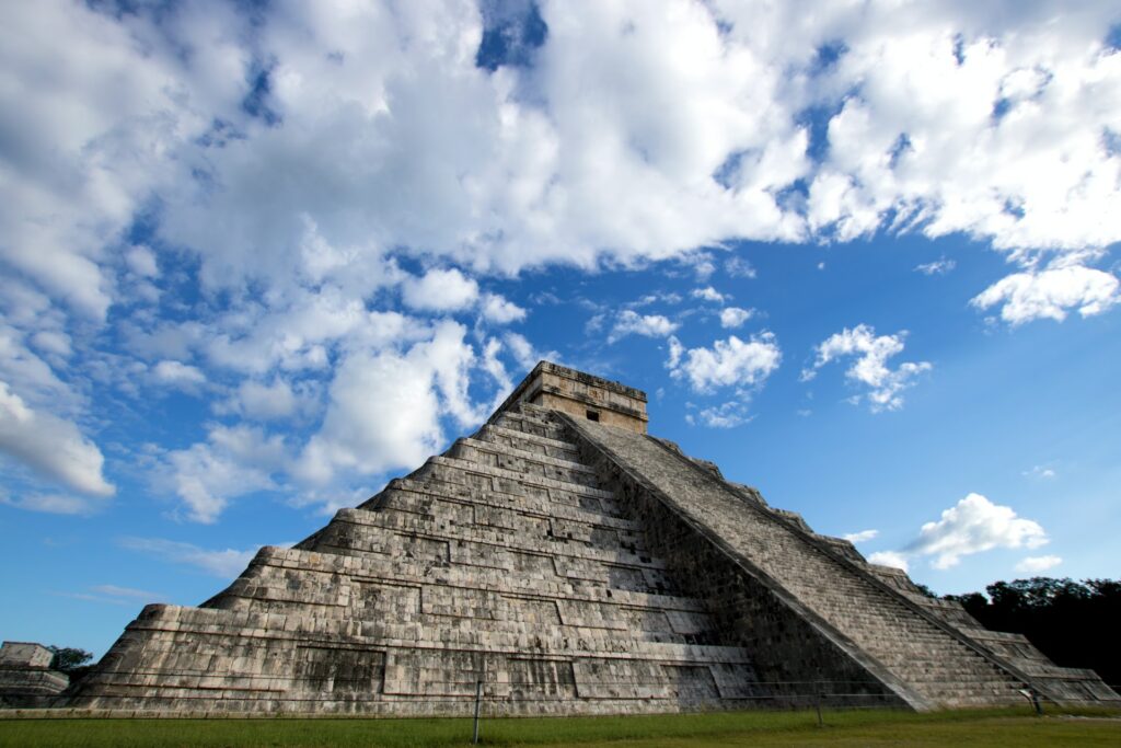 vista do Chichén-Itzá, em Yucatan, uma pirâmide de degraus enorme de pedra com uma rampa que chega até o topo, o céu é azul com nuvens, que pode ser visitado com o chip internacional México