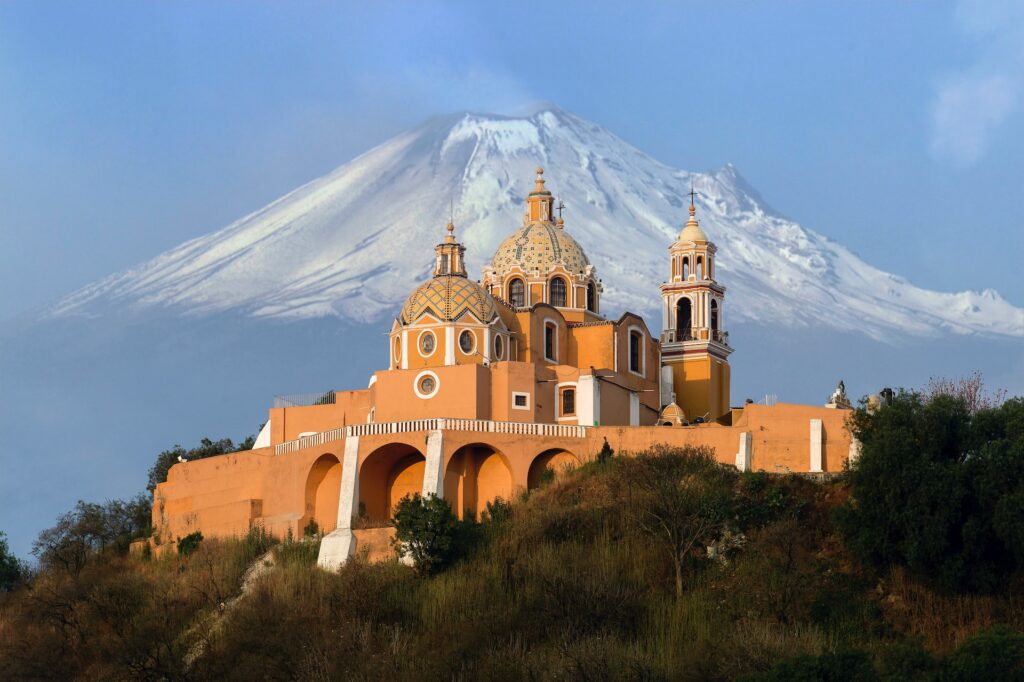 vista do Santuario de la Virgen de los Remedios, em San Pedro Cholula, no México, em tons alaranjados com uma montanha nevada ao fundo