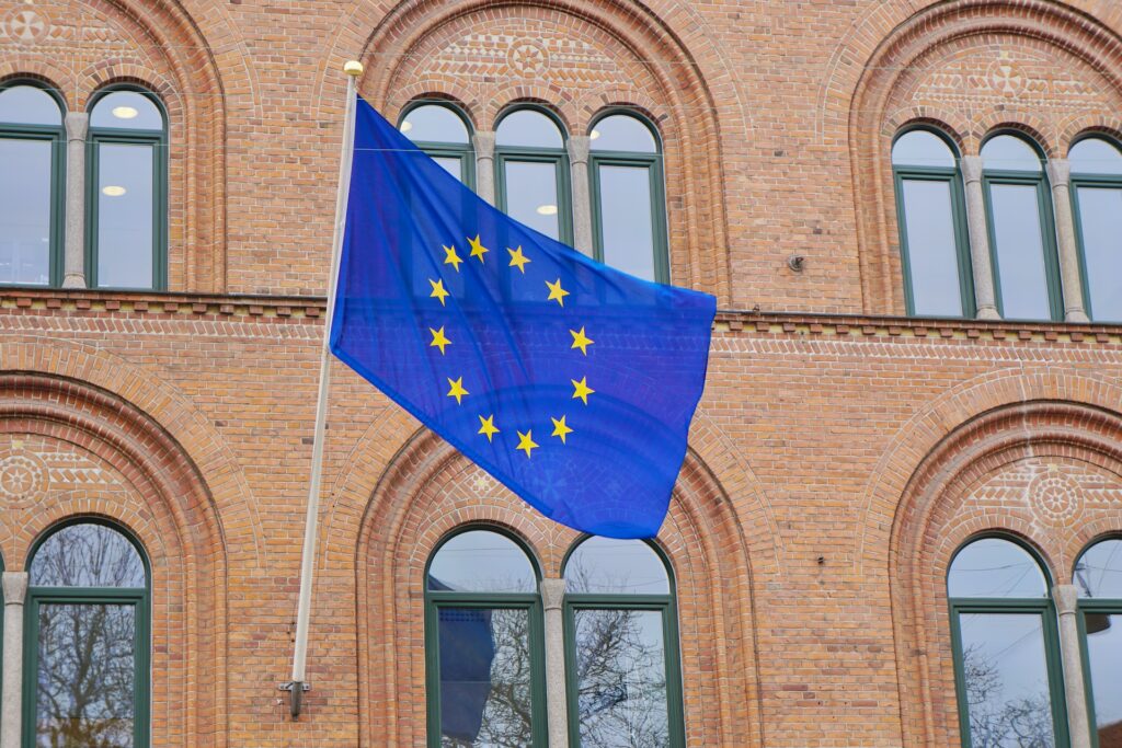 A bandeira da União Europei, azul com estrelas dourados formando um círculo, pendurada em um prédio na Dinamarca