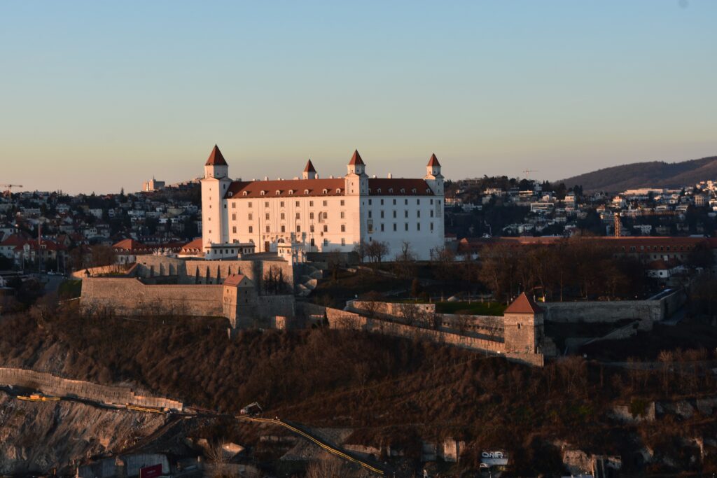 Vista de frente do Castelo Bratislava em cima de um monte durante o dia. Representa internacional para a Eslováquia.