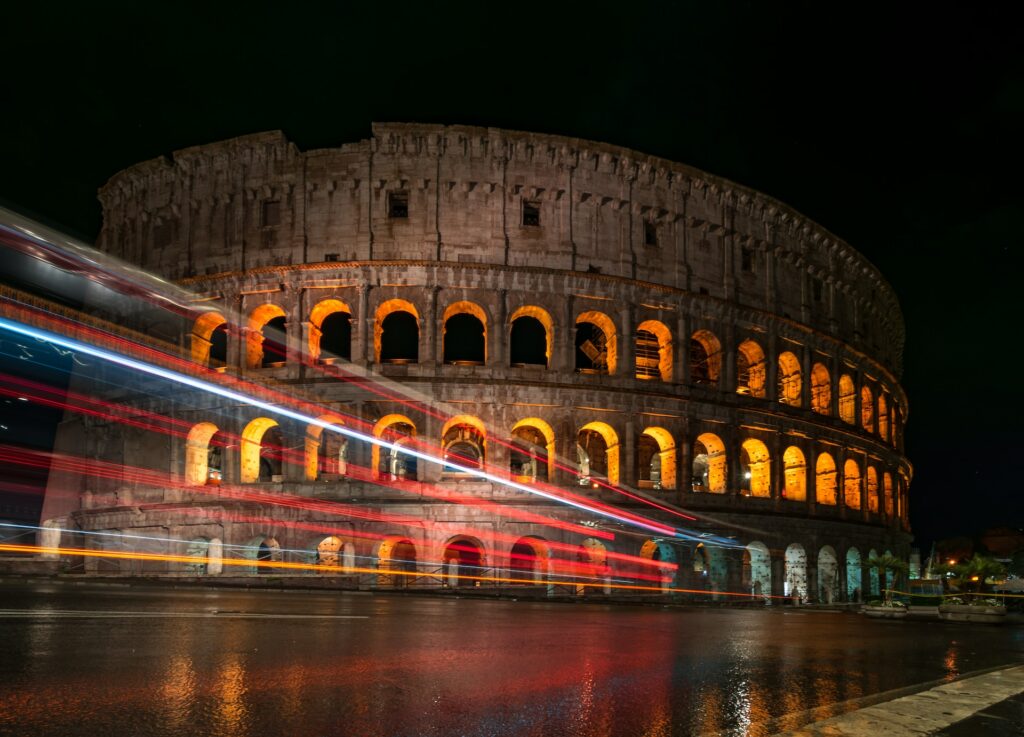 vista do Coliseu à noite com iluminação vinda de dentro com luzes marcadas de carros que passaram na rua, que pode ser postada com o chip internacional para Roma