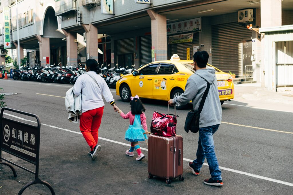 Família com três pessoas andando na rua com mala. Representa seguro viagem Multidestinos.