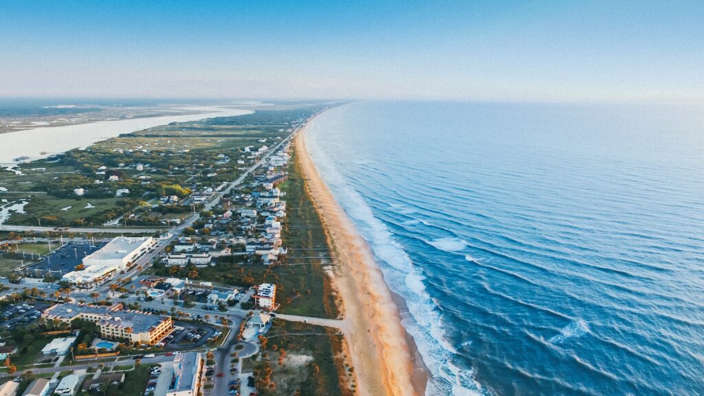 Vista de cima da praia de St. Augustine, Flórida, durante o dia com mar, areia e casas.