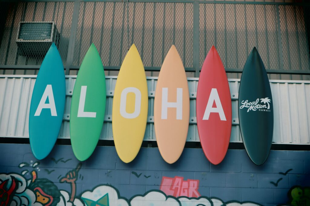Decoração em formato de pranchas de surf coloridas escrito "aloha" pregadas na parede para representar o chip internacional para o Havaí. 