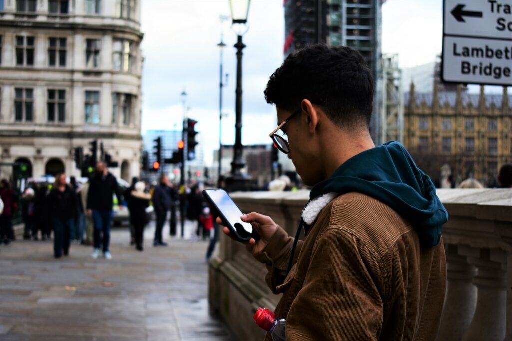 Um rapaz na Piccadilly Circus em Londres segurando um celular, para representar chip internacional para Londres