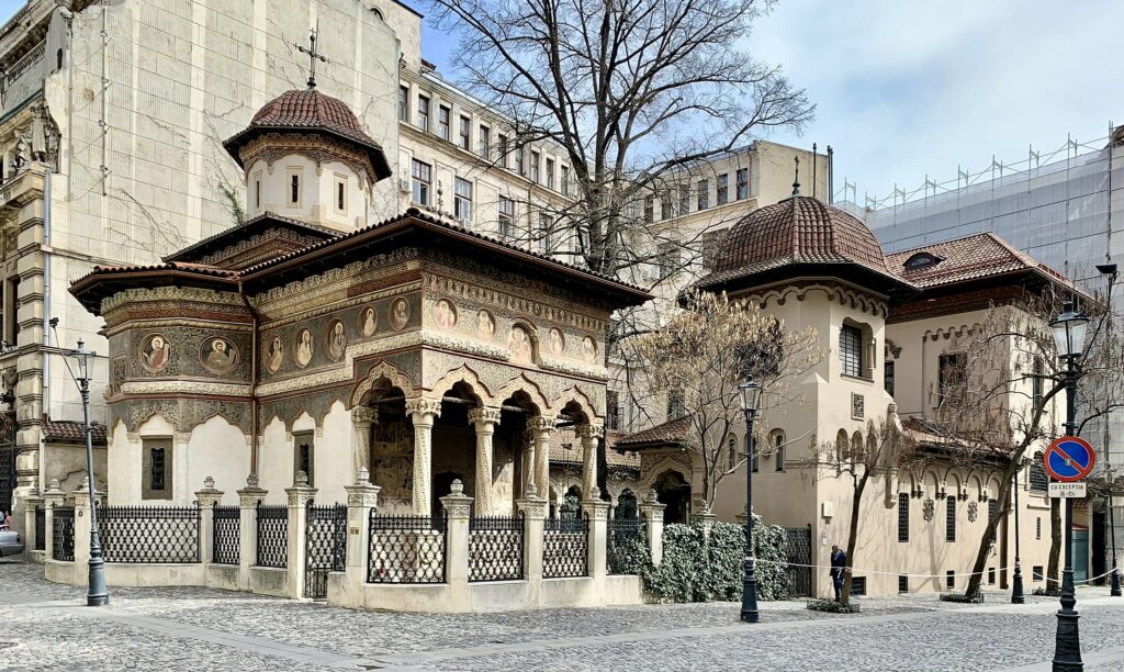fachada do Monastério Stavropoleos com muitos detalhes em arco e em pinturas, que pode ser visitado com o auxílio de um seguro viagem para Bucareste