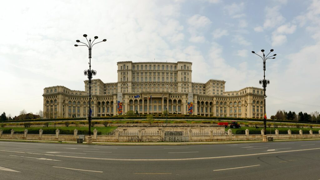 fachada do Palatul Parlamentului, o palácio de governa na Romênia, com a rua na frente e arquitetura da época comunista, que pode ser visitado com o seguro viagem para Bucareste