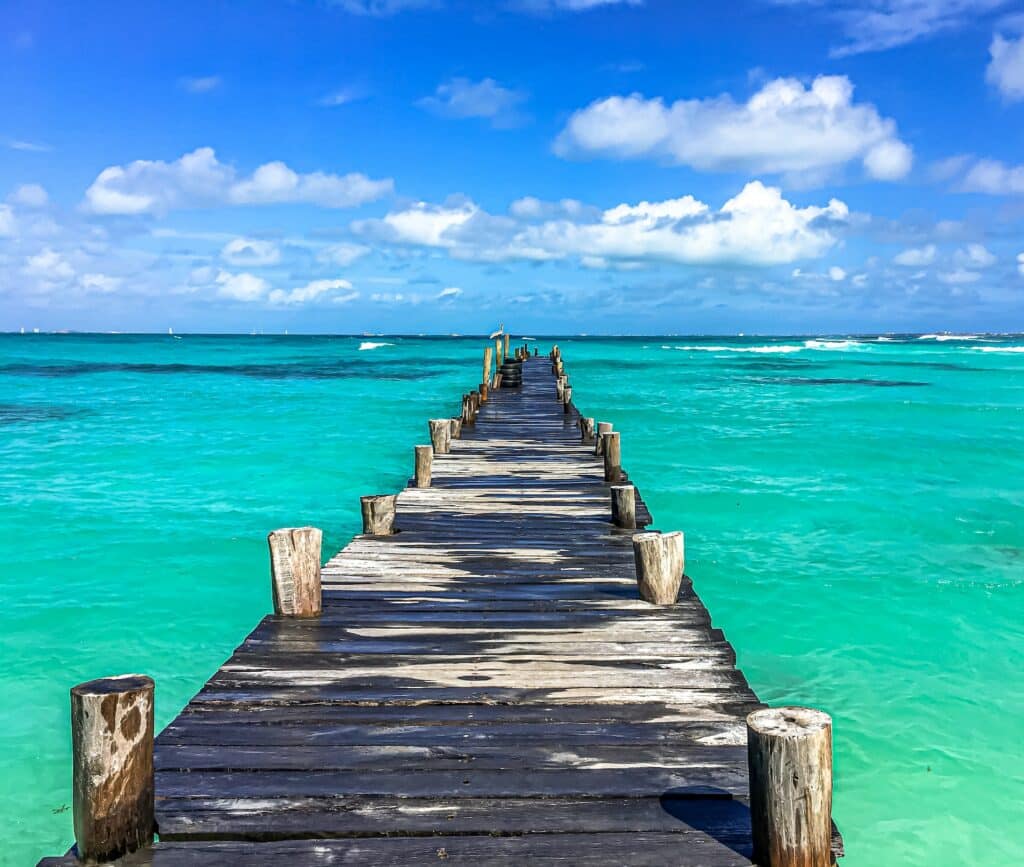 Pier no mar cristalino para ilustrar o post sobre chip internacional para Cancun. A foto foi tirada de dia e o céu é azul acima. - Foto: Andreas M via Unsplash